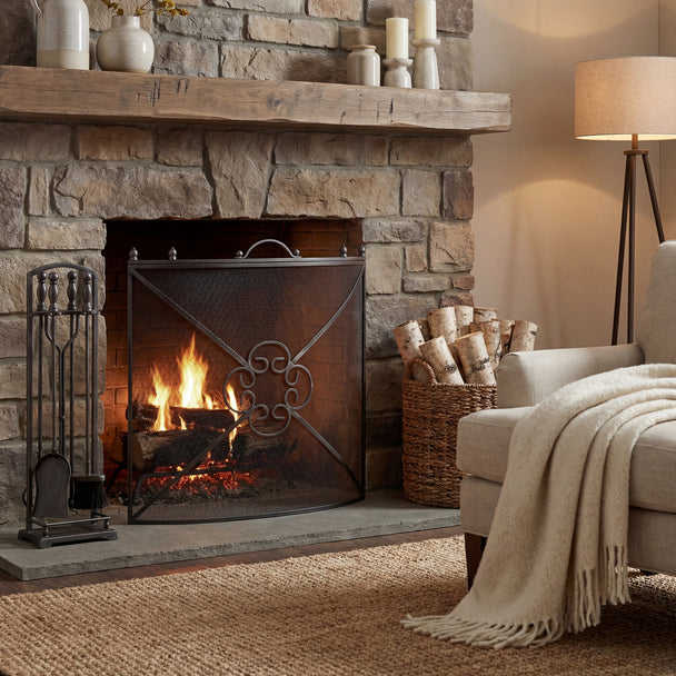 Mesh fireguard in front of a lit stone fireplace