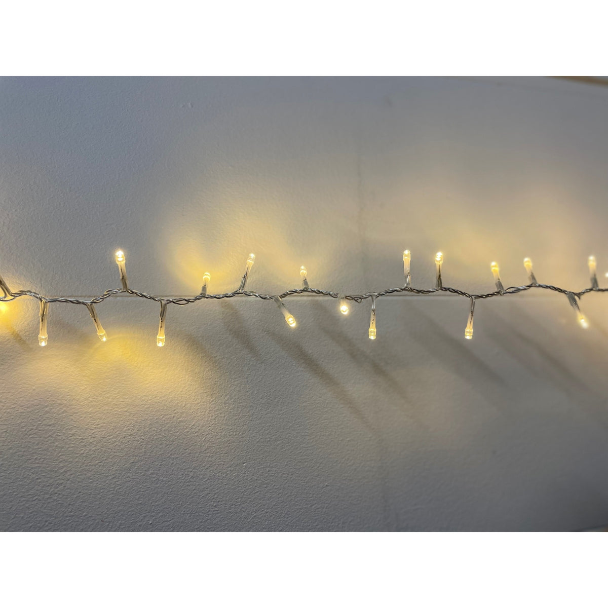 Warm white LED string lights glowing along a pale wall