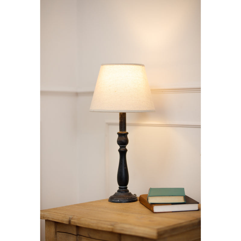 Ravenna lamp lit on a wooden bedside table with books