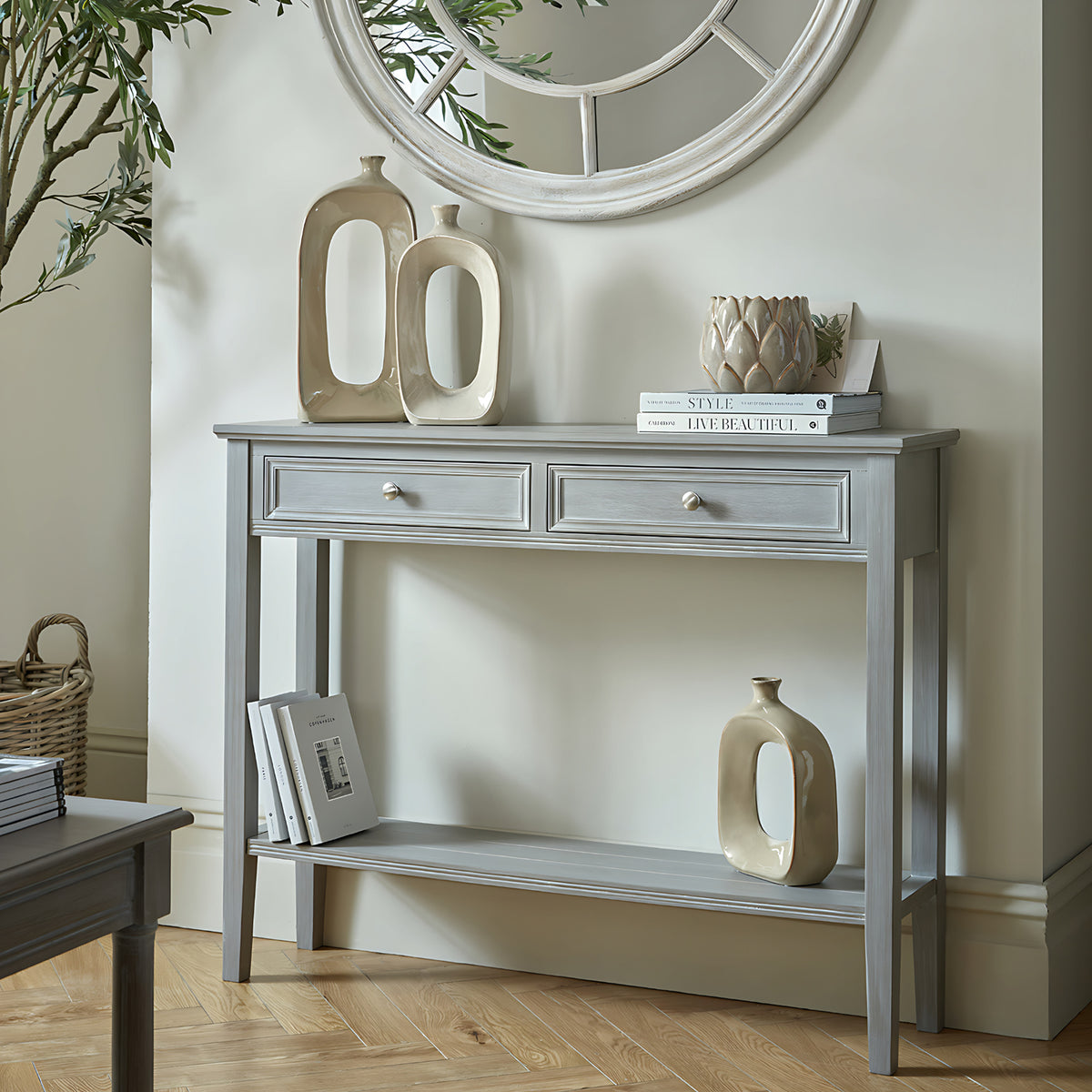 Serene grey two-drawer console table styled under a round mirror