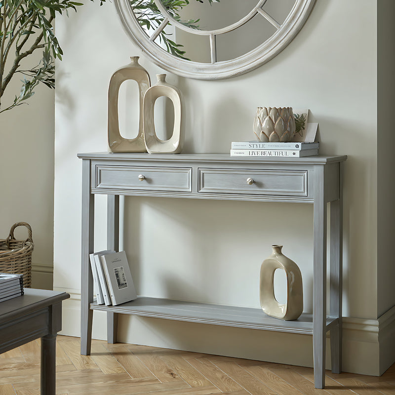 Serene grey two-drawer console table styled under a round mirror