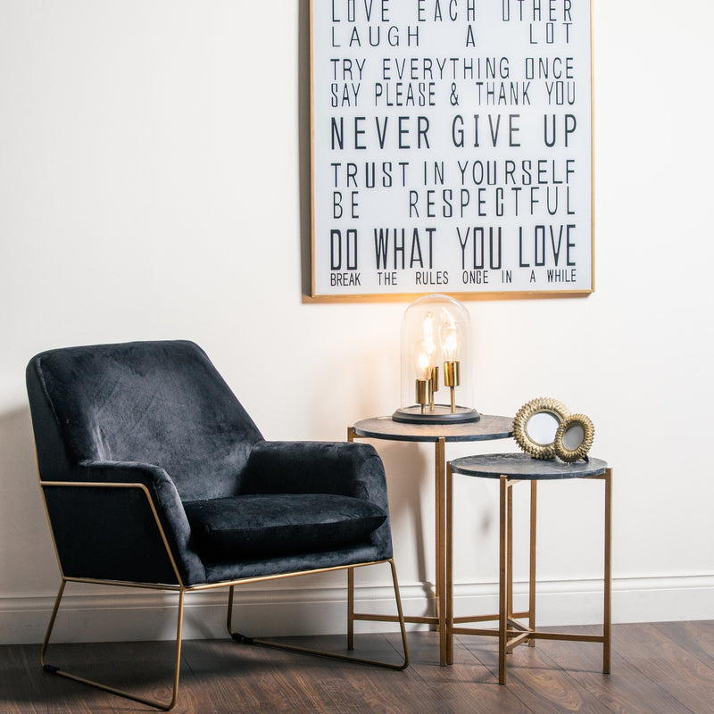 black marble nesting tables beside a velvet armchair