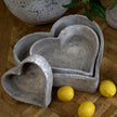 Stone-effect heart dishes on a wooden table with lemons
