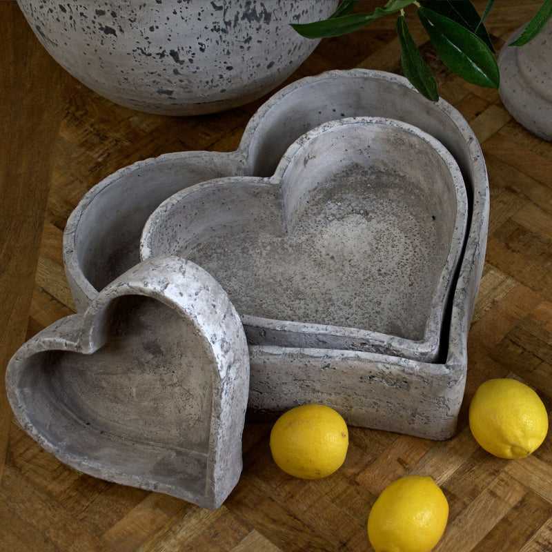 Stone-effect heart dishes on a wooden table with lemons