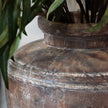 Close-up of the large pot's weathered finish beside a plant