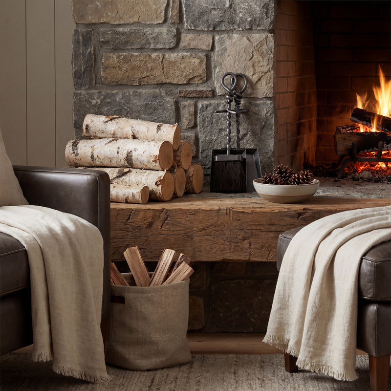 Hearth tidy set on a stone hearth beside a lit fire