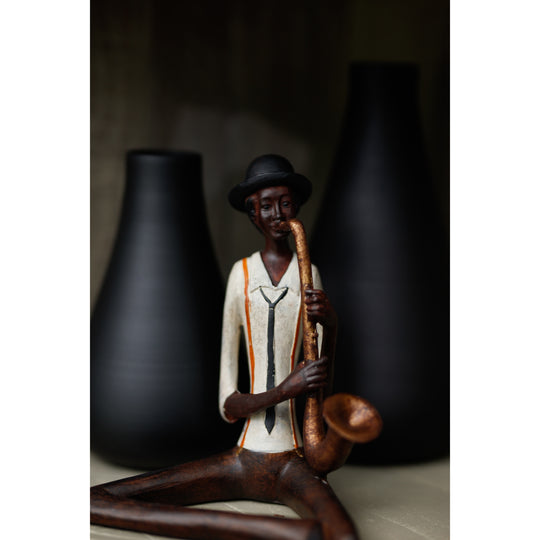 Seated saxophonist figurine in front of black vases