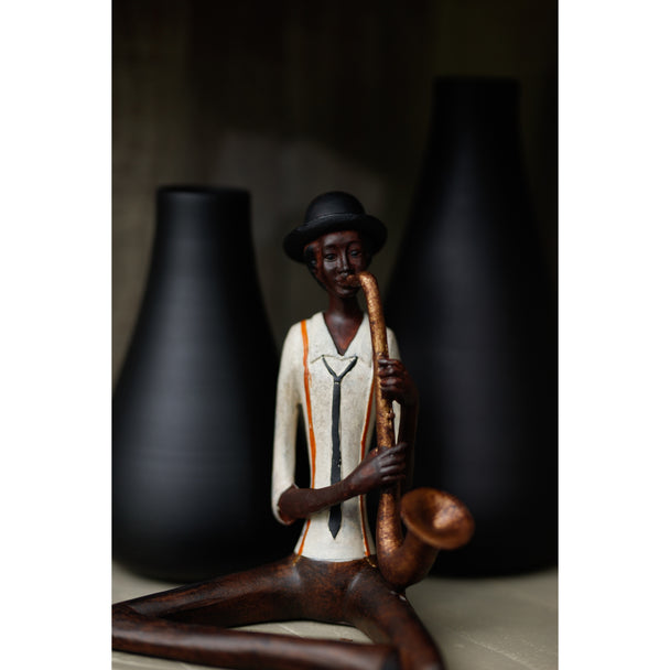 Seated saxophonist figurine in front of black vases