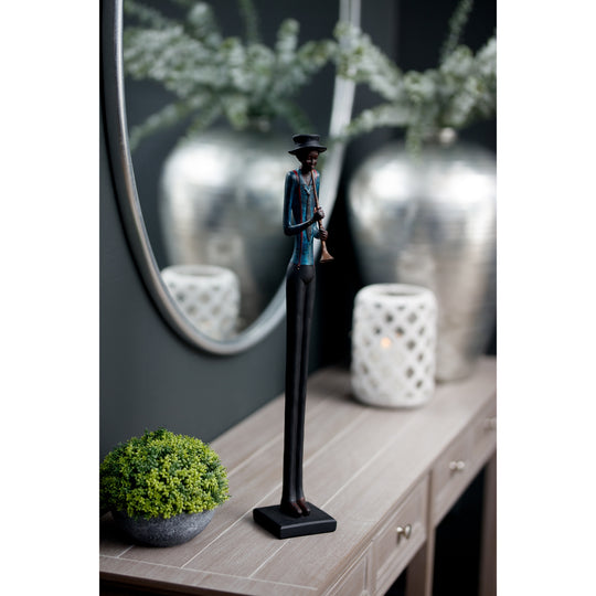 Jazz trumpeter figurine on a console table beside silver vases