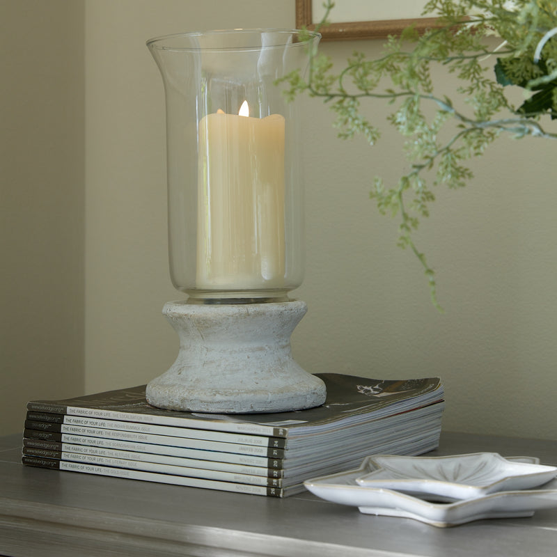 Cream stone hurricane lantern with an LED pillar candle on a stack of books
