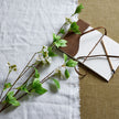 mock orange stems laid on linen with a leather bag