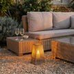 Tapered wicker lantern glowing beside a rattan sofa set