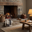 Antique pewter companion set beside a lit stone fireplace