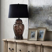 White washed photo frames on a wooden sideboard beside a lamp