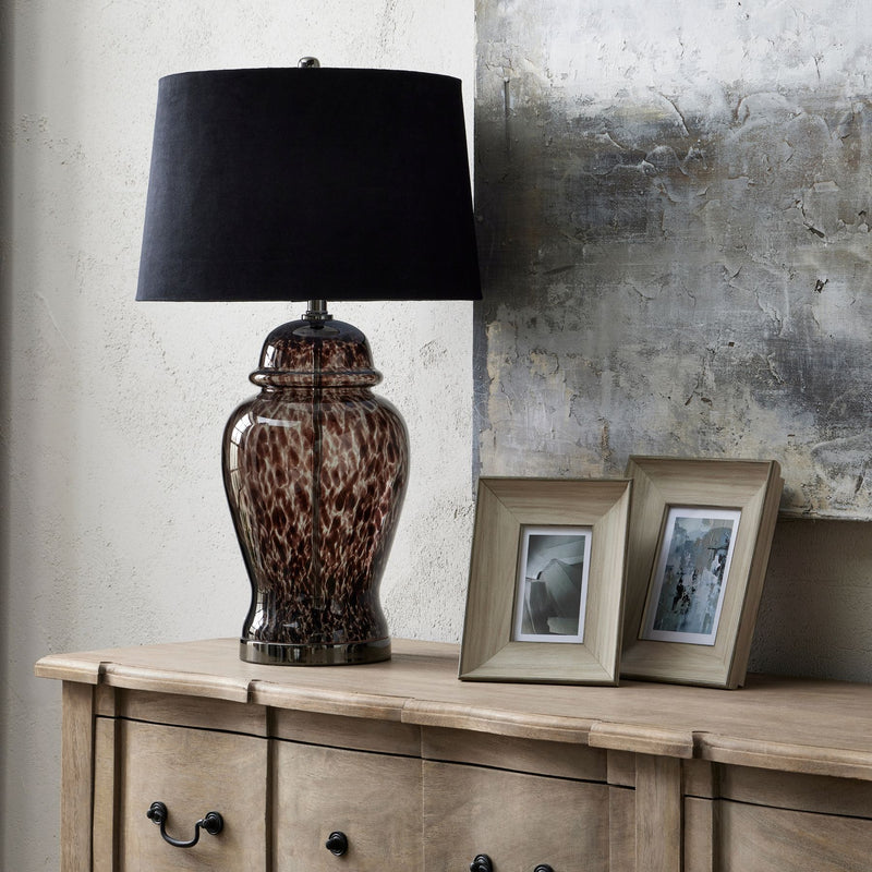 White washed photo frames on a wooden sideboard beside a lamp